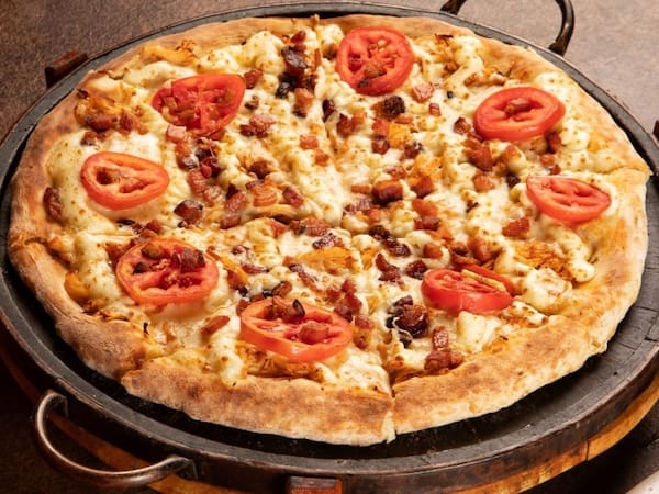 Pizza da La Parmigiana com queijo, tomate e bacon em uma assadeira rústica